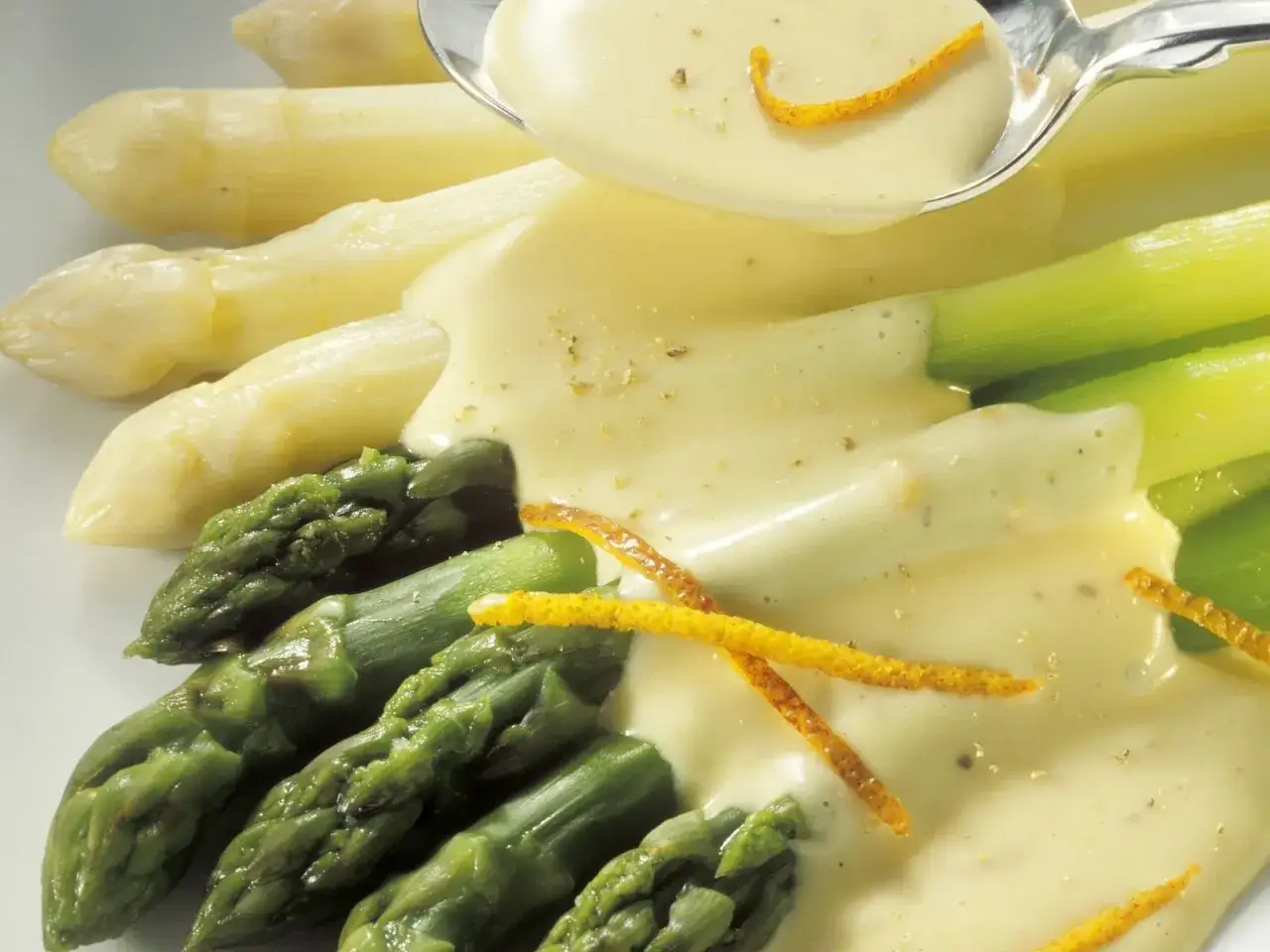 Frischer grüner und weißer Spargel, perfekt gegart, wird mit einer cremigen Sauce und Orangenzesten serviert. Ein Genuss, der zeigt, wie einfach und köstlich Spargel kochen sein kann.
